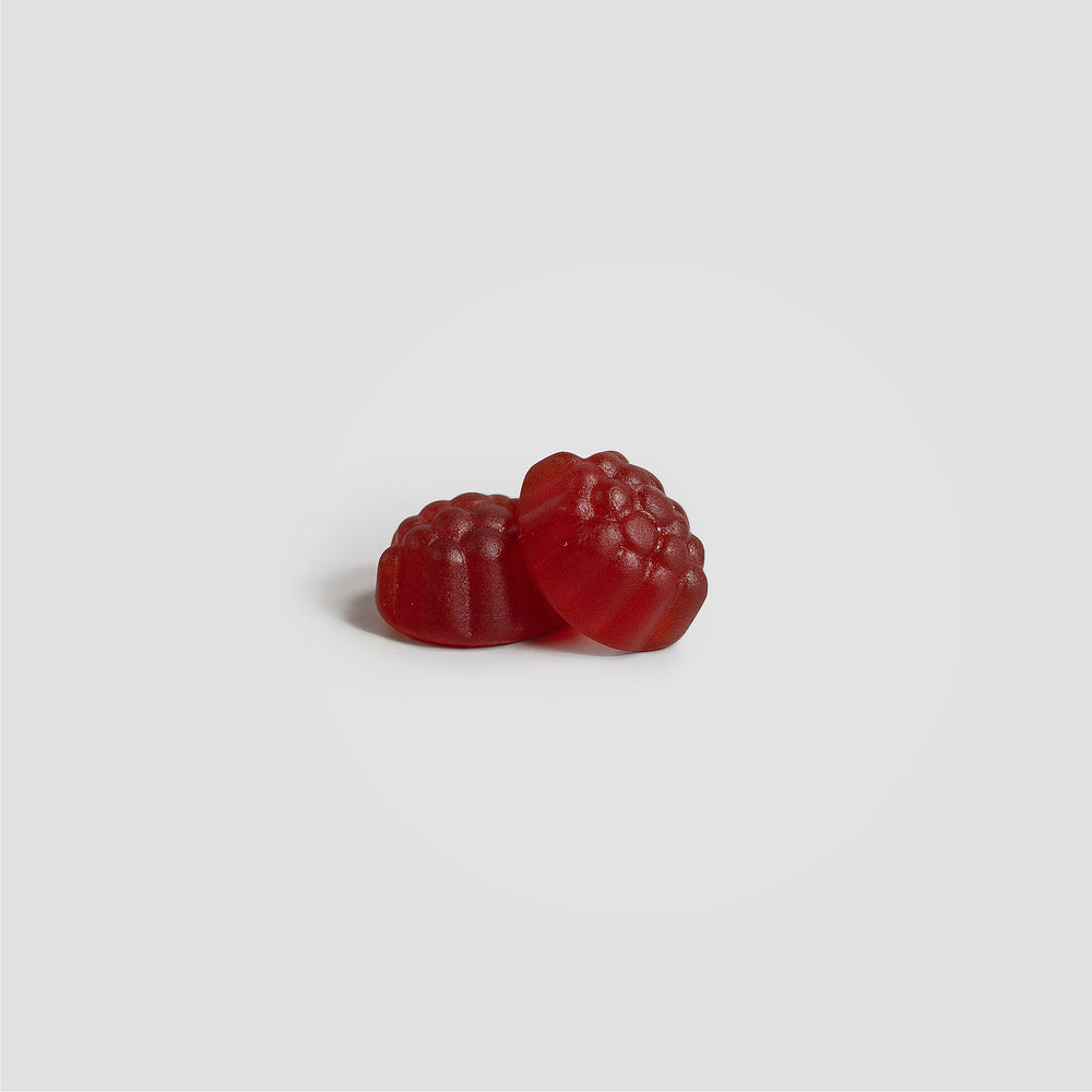Two bright red raspberry-shaped GreenHat Joint Support Gummies (Adult) rest on a plain light gray background.