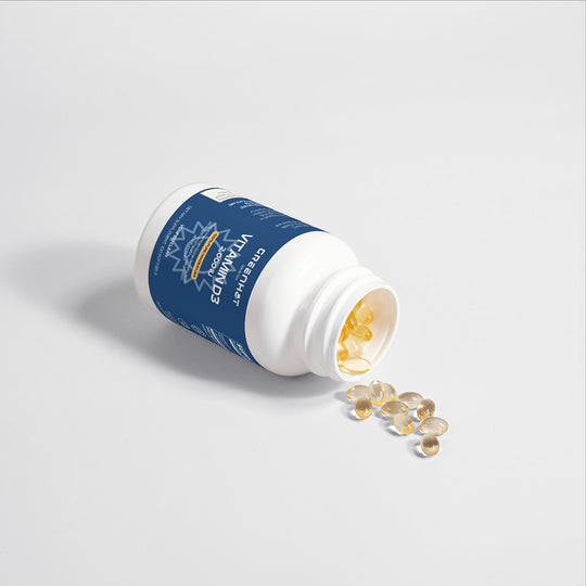 A white bottle with a blue label, labeled "Vitamin D3 - Strengthen Your Foundation," is on its side with several yellow capsules spilling out onto a white surface, essential for bone development and boosting energy levels.