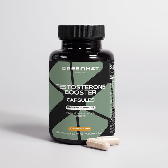 A black bottle labeled "GreenHat Testosterone Booster - Get The Most Out Of Yourself" is placed against a plain background. Two beige capsules are beside the bottle. The label indicates 90 capsules, "100% Pure/Made in USA," and includes Tribulus Terrestris for enhanced effectiveness.