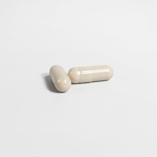 Two beige, translucent capsules on a plain white background, likely containing Testosterone Booster - Get The Most Out Of Yourself by GreenHat as a natural testosterone booster.