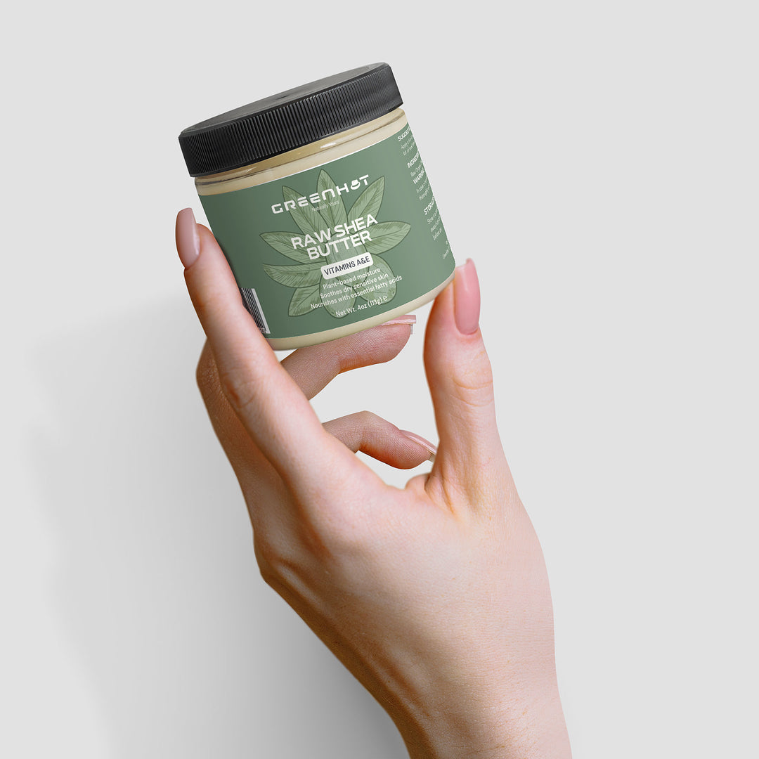 A hand holding a jar of GreenHat Raw Shea Butter, showcasing its green label with white text, promises unrefined goodness.