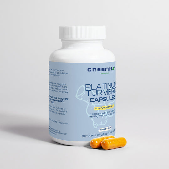 A white bottle labeled "Platinum Turmeric - Immunity Accelerator" with two yellow capsules beside it. The label mentions health benefits, including digestive health and joint pain relief, along with dosage instructions. The brand name "GreenHat" is displayed prominently at the top.