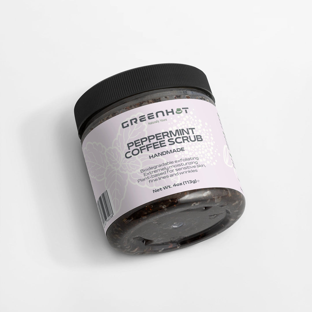 A jar of GreenHat Peppermint Coffee Scrub with a black lid, featuring a pink label that describes it as handmade and rich in antioxidants for effective exfoliation, removing dead skin, and reducing wrinkles. Net weight: 4 oz.