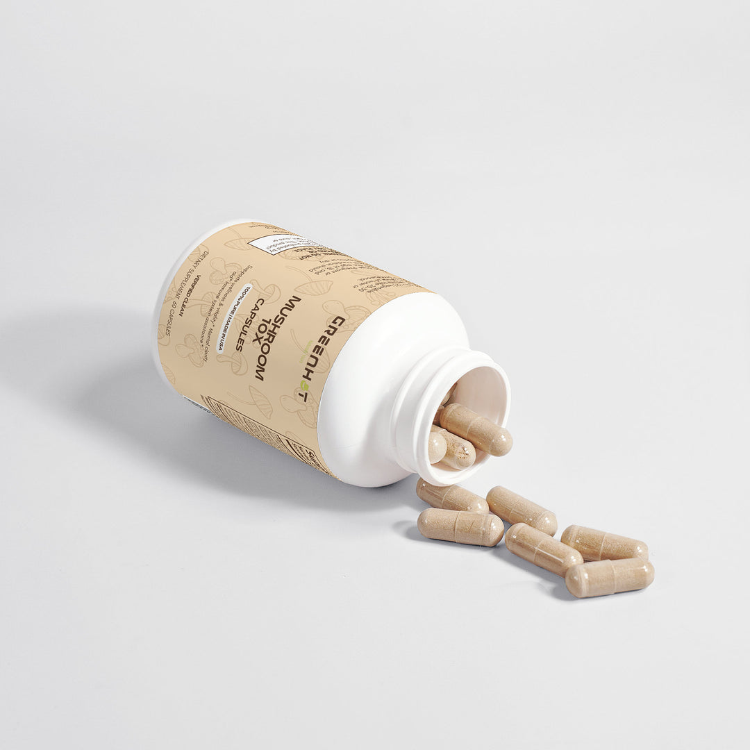 A bottle labeled "Mushroom Complex 10 X - Natural Power" by GreenHat lies on its side with several beige, adaptogenic capsules spilling out, incorporating powerful medicinal mushrooms for enhanced wellness.