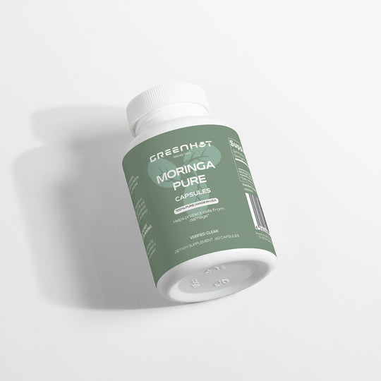 A white bottle with a green label titled "GreenHat Moringa Pure - Enhance Cellular Health." The label notes that it contains 60 capsules under dietary supplement. Known as a superfood, Moringa Oleifera adds a natural boost to your daily regimen.