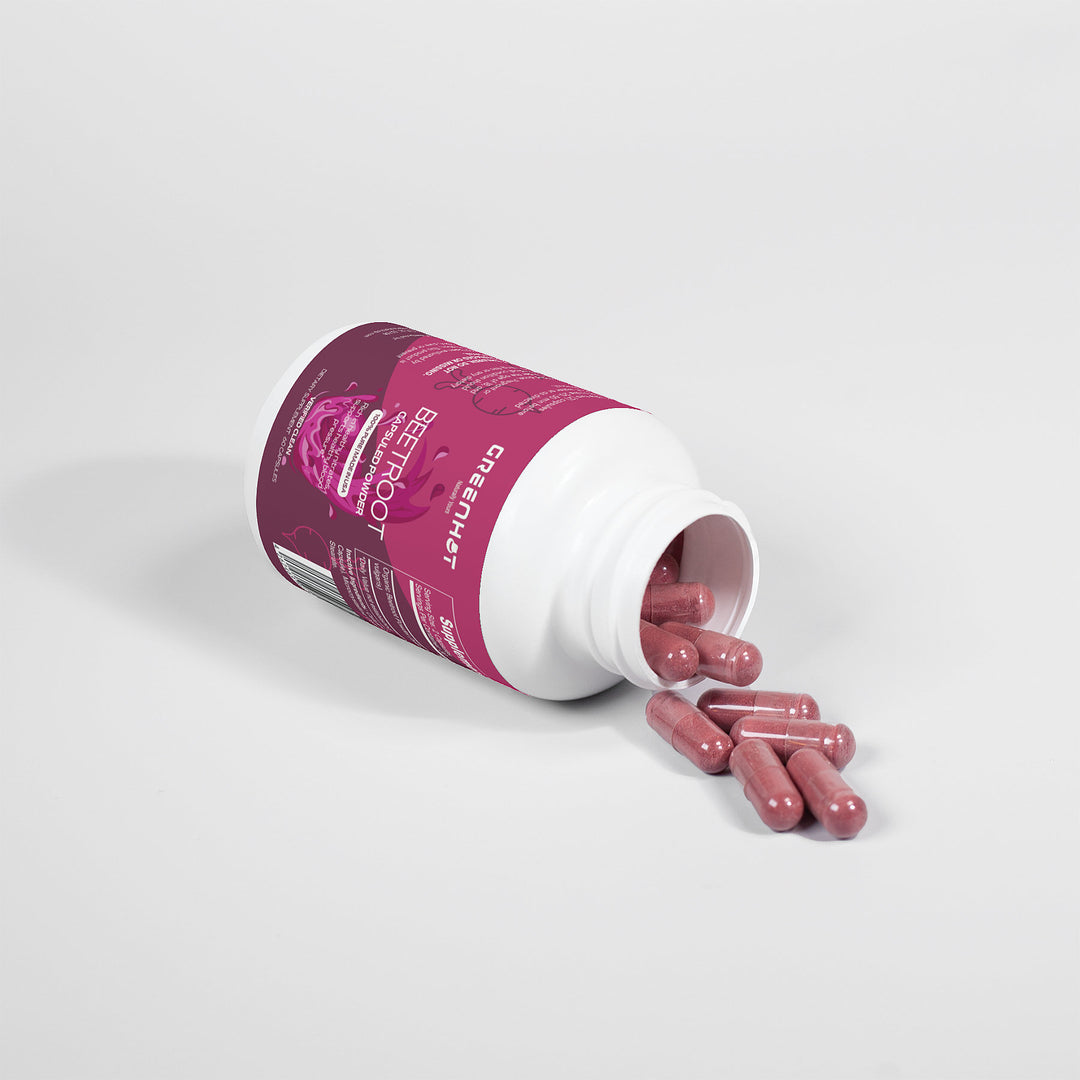 A white bottle with a purple label, partially tipped over, spilling out several pink capsules rich in antioxidants onto a white surface. The label reads "Beetroot - Natural Energy Booster" by GreenHat.