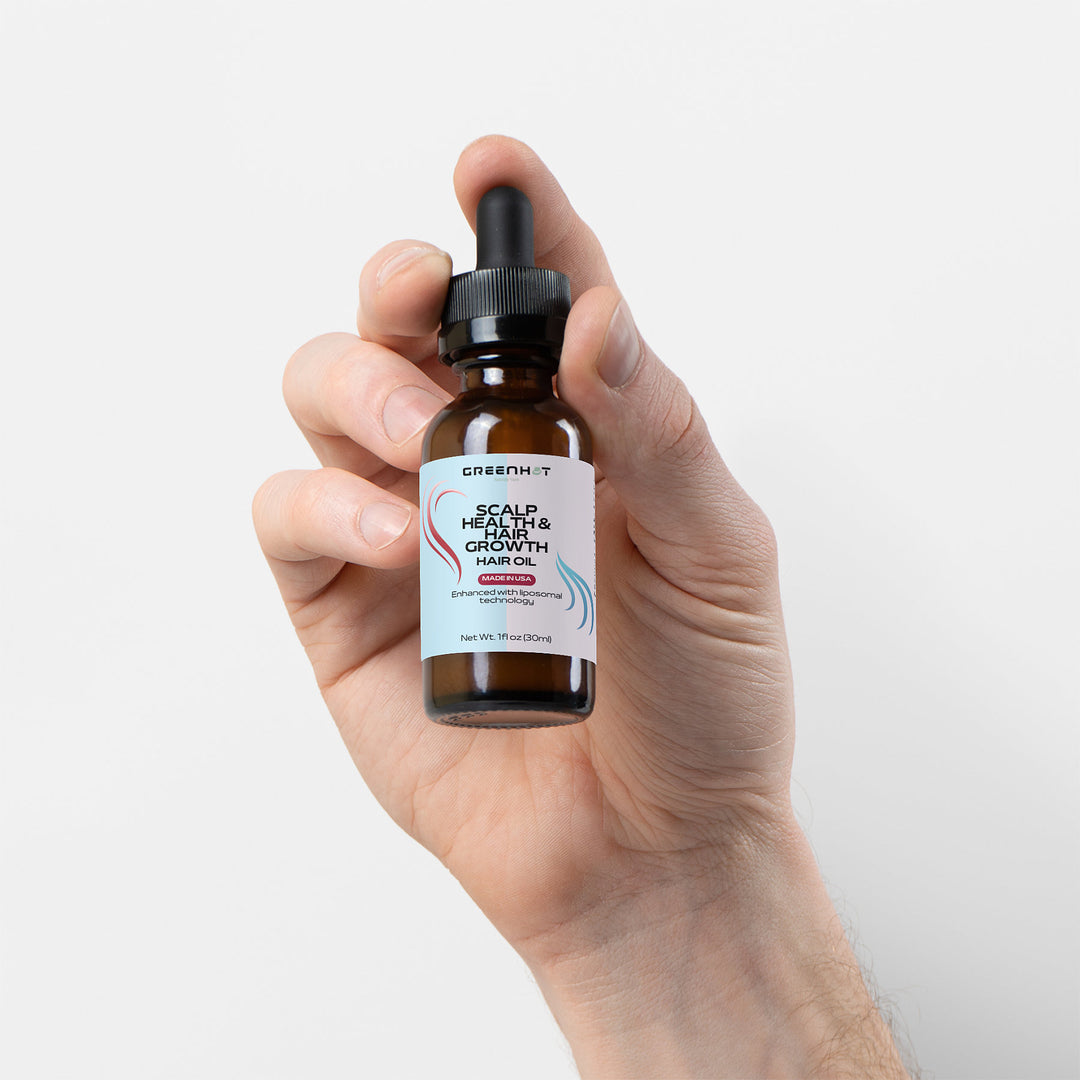 A hand holding a small brown bottle of "GreenHat Scalp Health & Hair Growth Hair Oil," featuring a dropper cap and a white label with blue and black text, showcases the power of natural oils for optimal scalp health and hair growth.