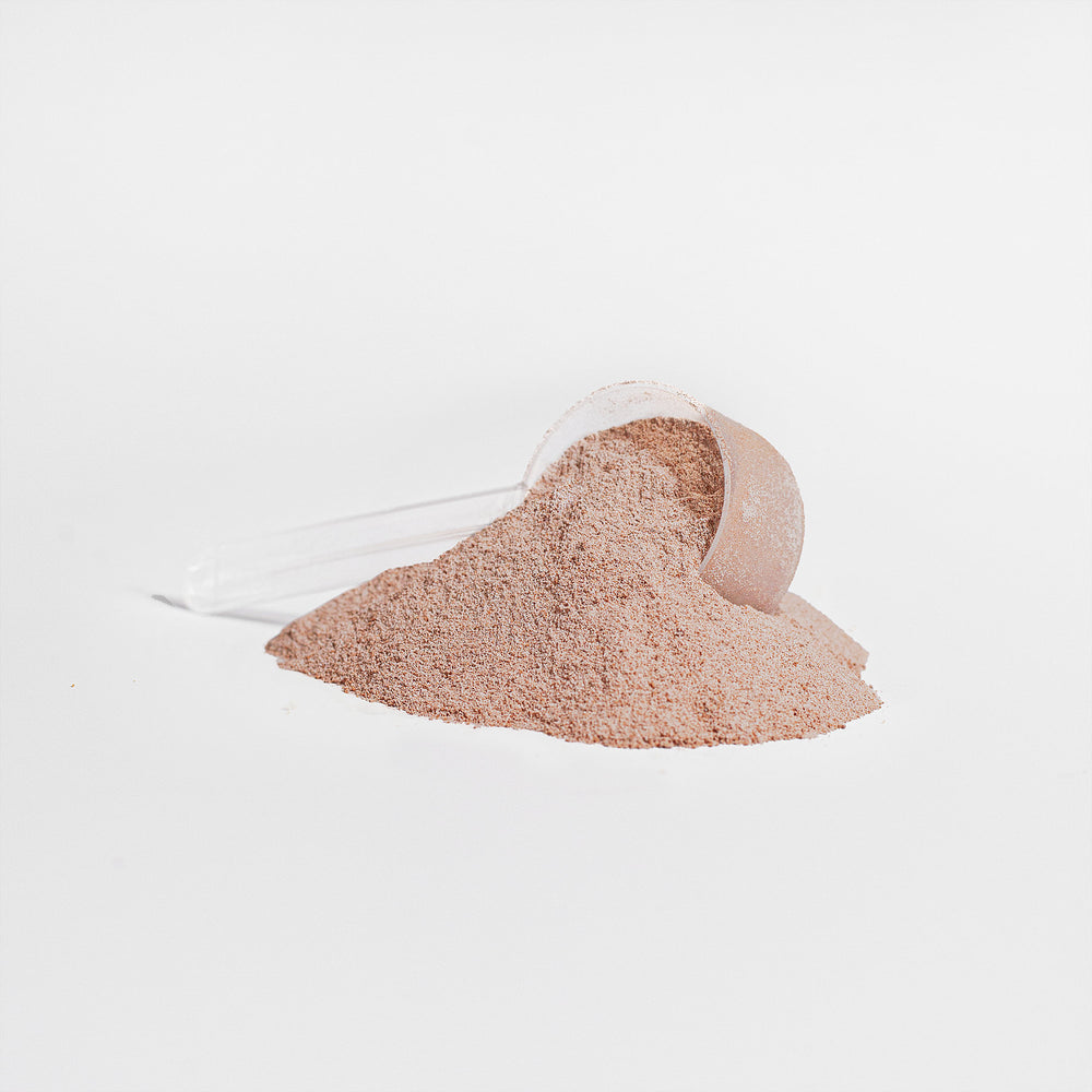 A scoop of GreenHat Grass-Fed Collagen Peptides Powder (Chocolate) overturned, spilling its contents on a plain white background.