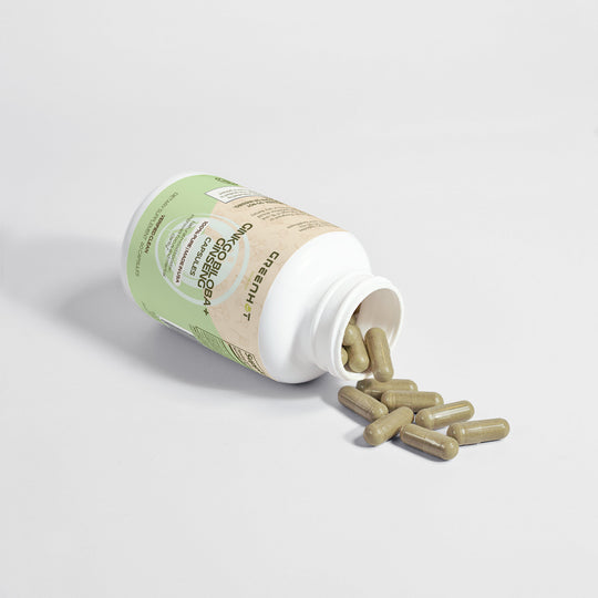 A bottle of Ginkgo Biloba + Ginseng capsules by GreenHat tipped over with several capsules spilled out on a white surface.