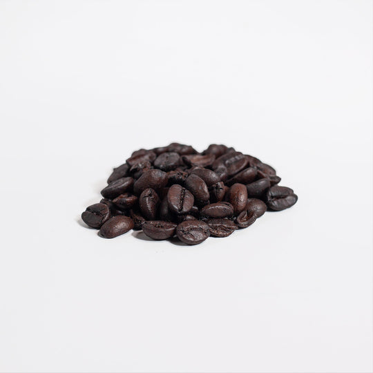 A pile of GreenHat Brazilian Blend 4oz - 100% Arabica coffee beans on a plain white background.