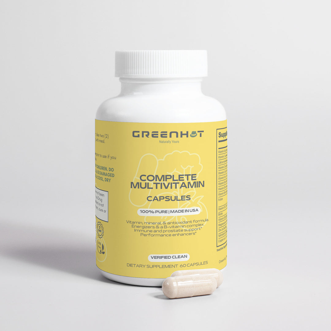 A white bottle labeled "GreenHat Complete Multivitamin" with a yellow label is standing upright. Two capsules lie beside it. The bottle contains 60 dietary supplement capsules formulated with immune-boosting herbs and antioxidants.