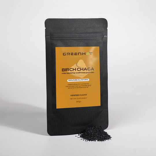 A black pouch labeled "GreenHat Birch Chaga Microbiome Wellness Powder" stands upright. In front of it, a small pile of black powder is shown. The label states "100% Pure All Natural" and other benefits, highlighting its rich phytochemicals for a boosted immune system.