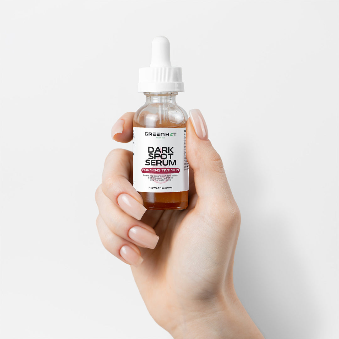 A hand is holding a bottle of GreenHat Dark Spot Serum for Sensitive Skin with natural extracts, designed specifically for sensitive skin, complete with a white dropper cap.