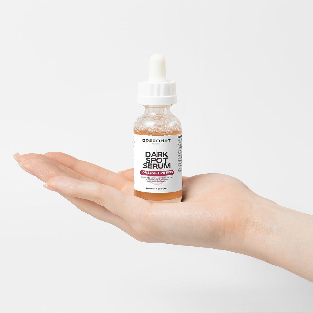 A hand holding a bottle of Dark Spot Serum for Sensitive Skin with natural extracts for sensitive skin by GreenHat, featuring a dropper cap.