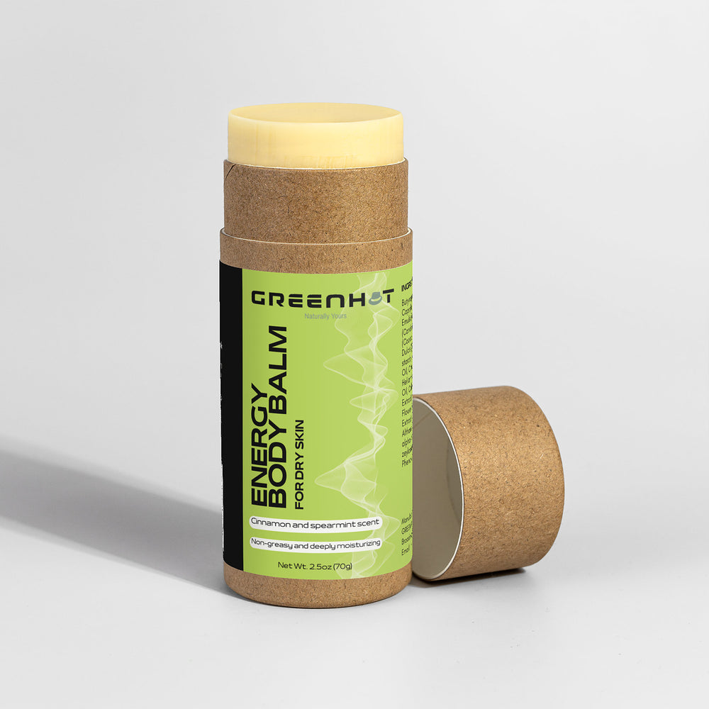 A cardboard push-up tube labeled "GreenHat Energy Body Balm" on a white background. The balm has a yellowish color and the label indicates a cinnamon and spearmint scent, suitable for dry skin. This eco-friendly body balm offers a moisturizing treatment for all skin types.