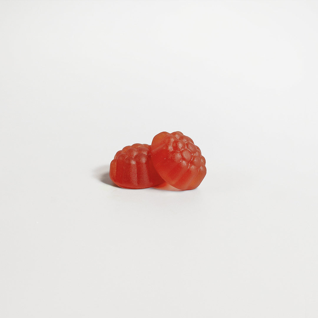 Two red GreenHat Sleep Well Gummies (Adult) shaped like raspberries against a plain white background.