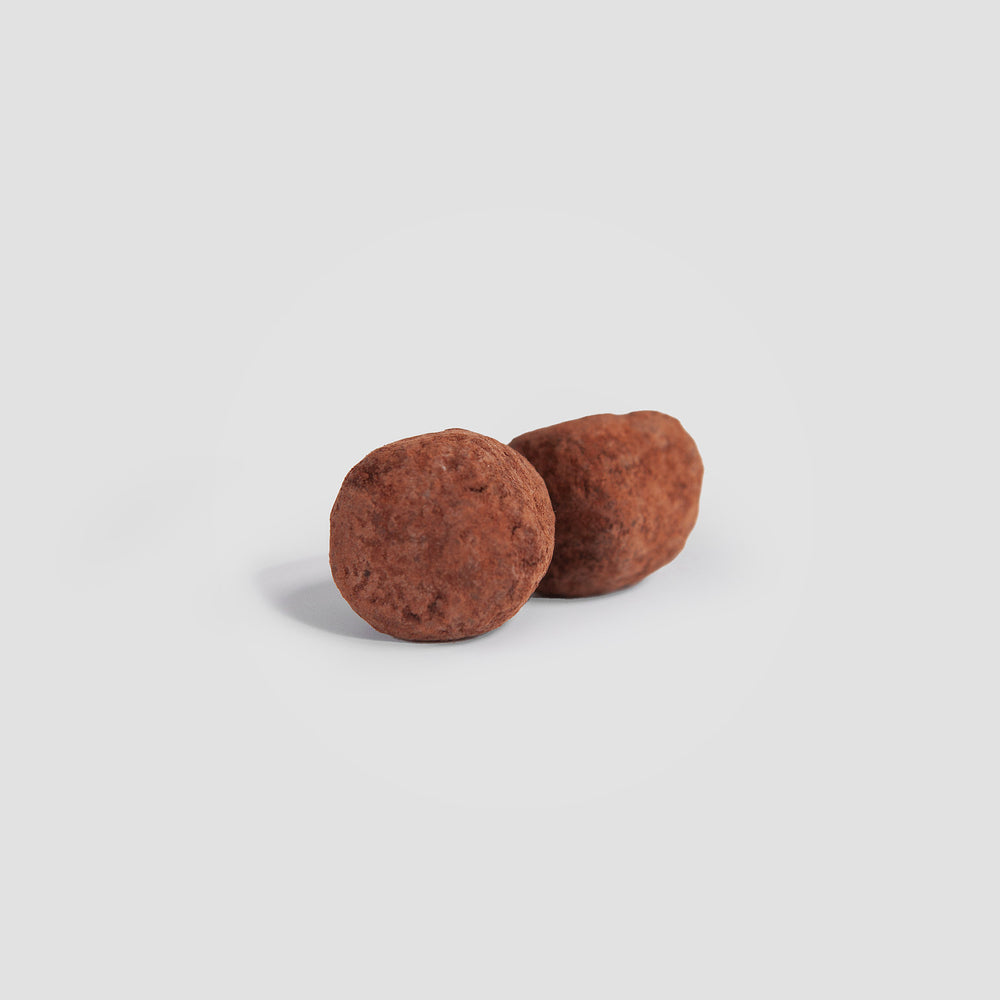 Two Birch Chaga Truffles from GreenHat, dusted with cocoa powder for immune system support, on a plain white background.