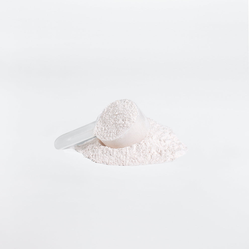 A white scoop partially filled with GreenHat BCAA Post Workout Powder (Honeydew/Watermelon), resting on a pile of the same powder against a bright white background.
