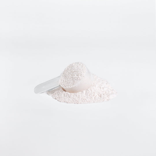 A white scoop partially filled with GreenHat BCAA Post Workout Powder (Honeydew/Watermelon), resting on a pile of the same powder against a bright white background.