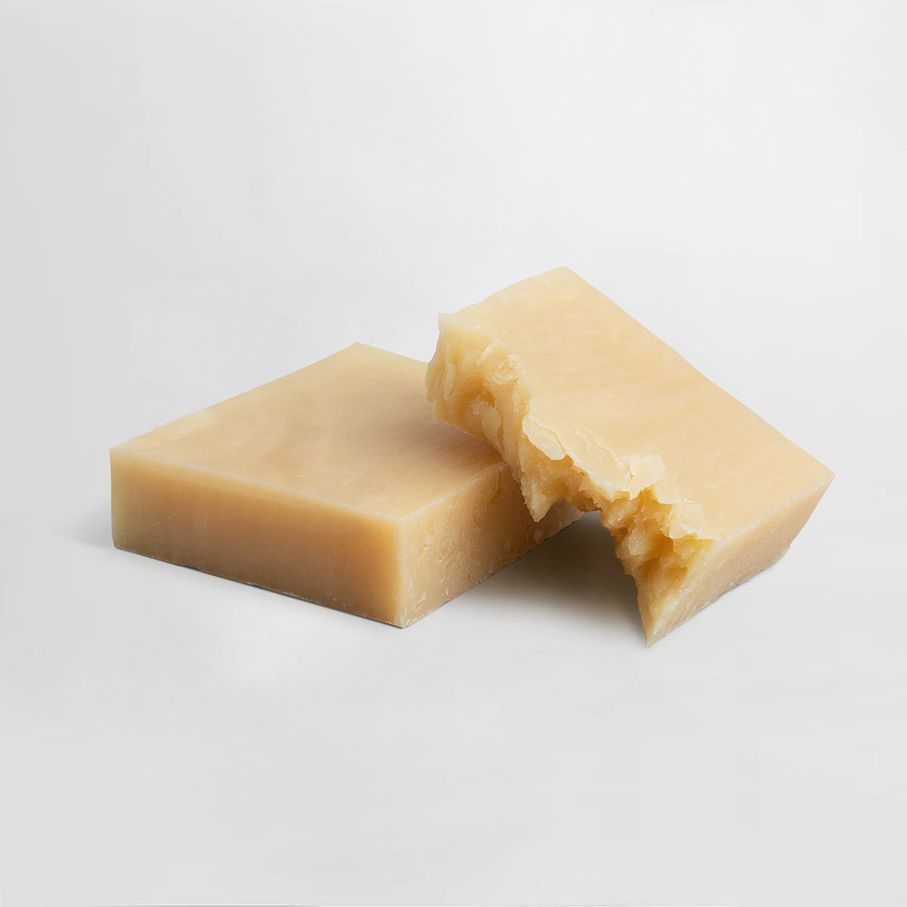 Two pieces of PurelyFresh Soothe Soap by GreenHat shaped like hard cheese with a bite taken out, set against a plain white background.