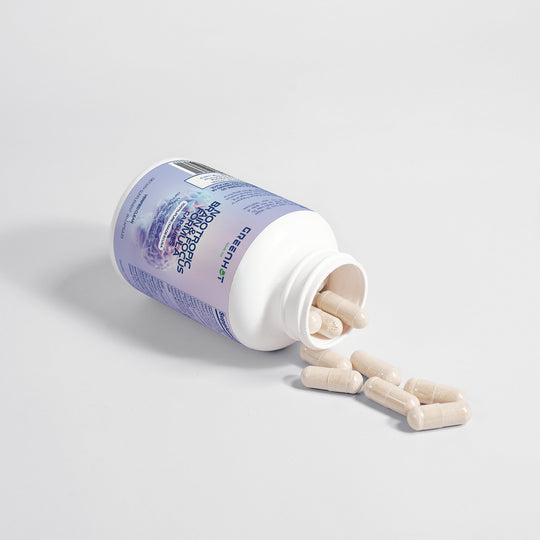A bottle of GreenHat Nootropic Brain & Focus Formula capsules, formulated to support cognitive function, tipped over with pills spilling out on a plain white surface.