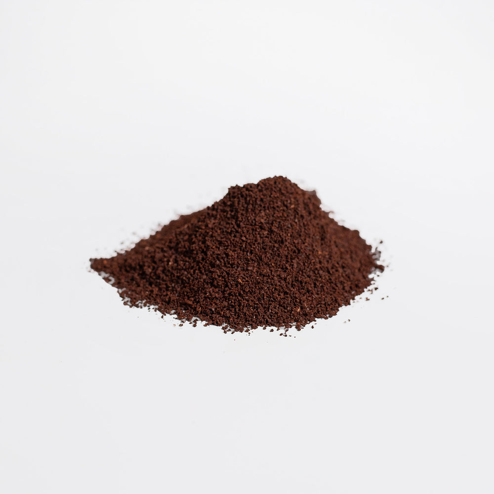 A neat pile of fine dark brown GreenHat organic hemp coffee blend - medium roast 16oz on a plain white background.