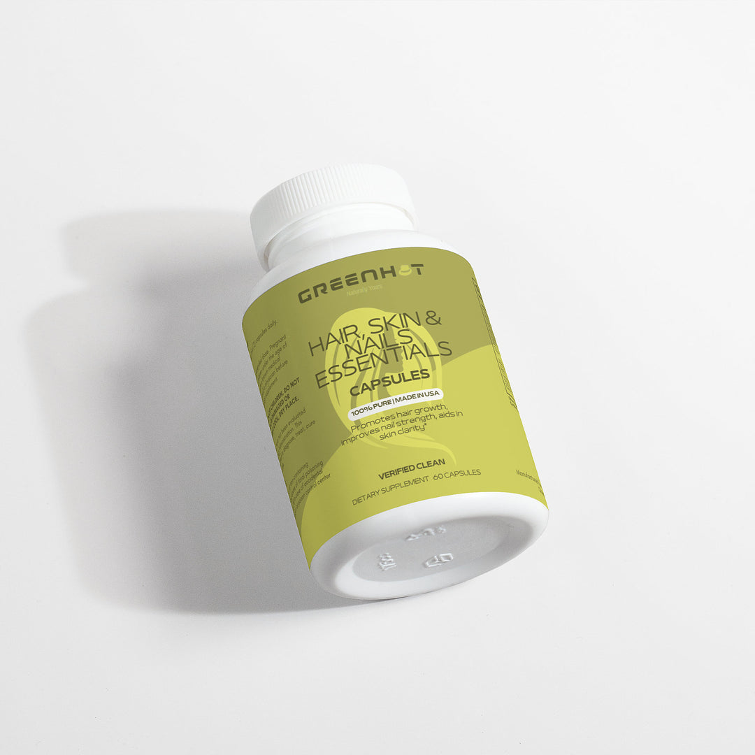 A bottle of GreenHat Hair, Skin and Nails Essentials supplement capsules lying on a white surface, labeled in green and yellow.